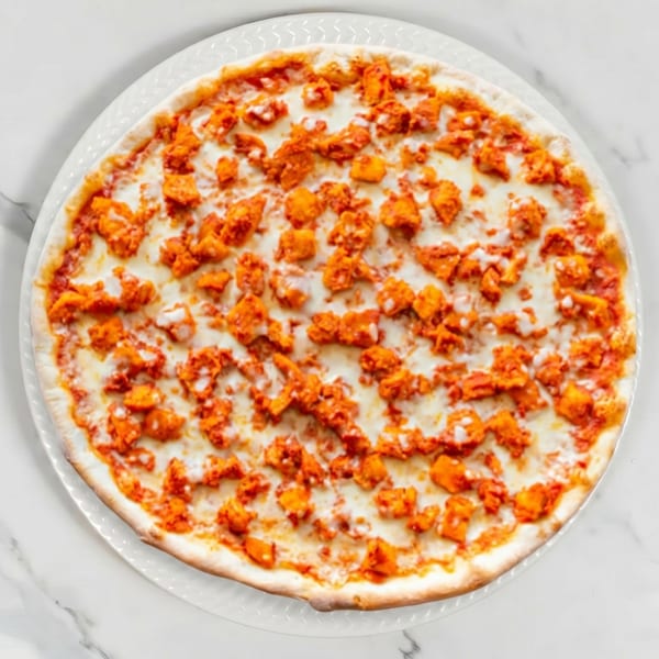 Top-down view of a whole buffalo chicken pizza with melted mozzarella cheese on a white plate.